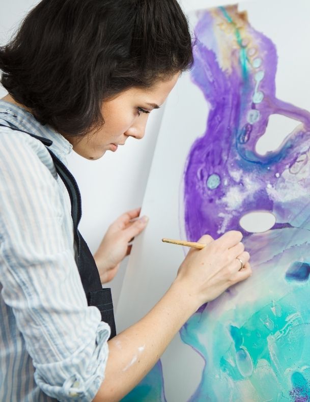 TaskForce Introduction to Art Skills course - Young woman painting over white canva with blue and purple paint